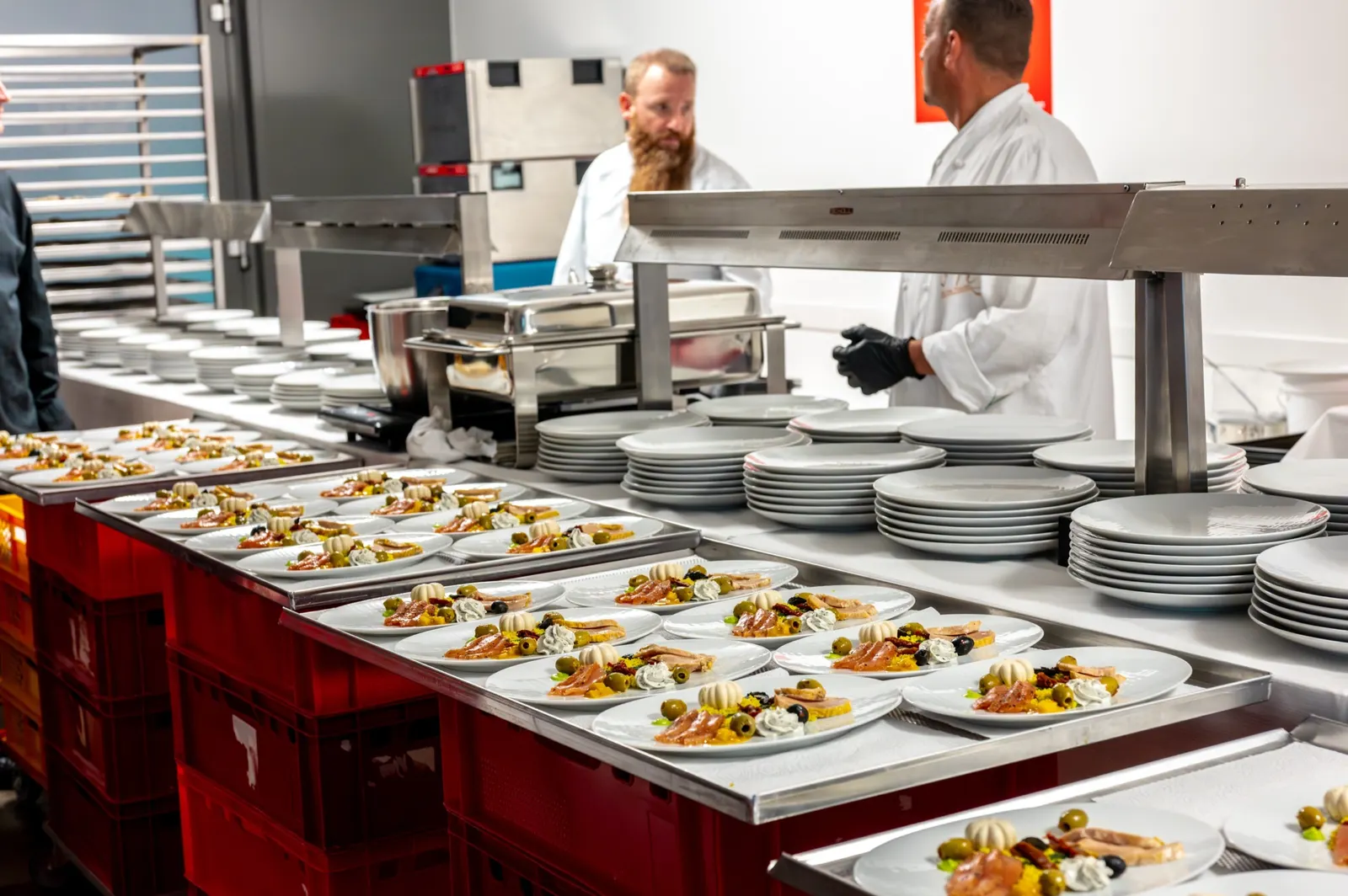 Köche richten an einer langen Ausgabe Teller für das Dinner an