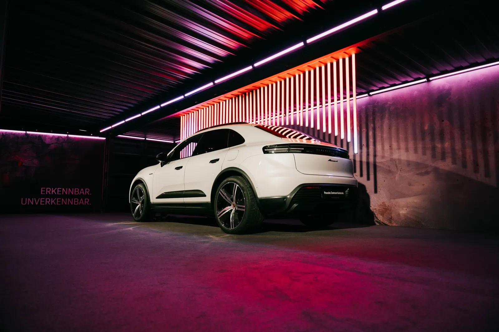 Weißer Porsche im Hangar vor einer Wand aus Lichtstreifen