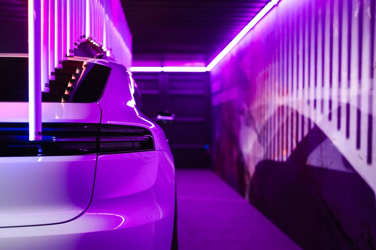 Heck eines Porsche im violetten Licht neben einer Lichtwand