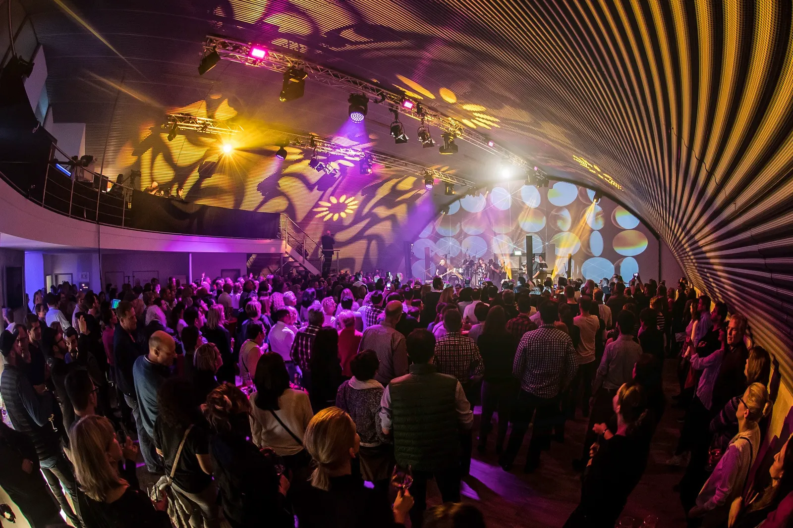 Volles Konzert im Hangar mit buntem Lichtmuster unter dem Bogendach