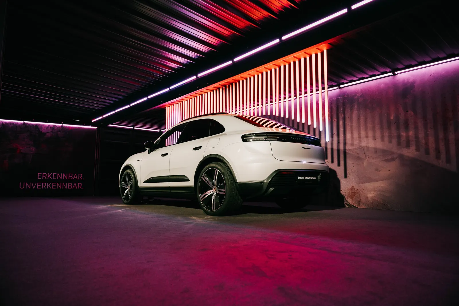 Weißer Porsche Macan unter roten Lichtstreifen im Hangar