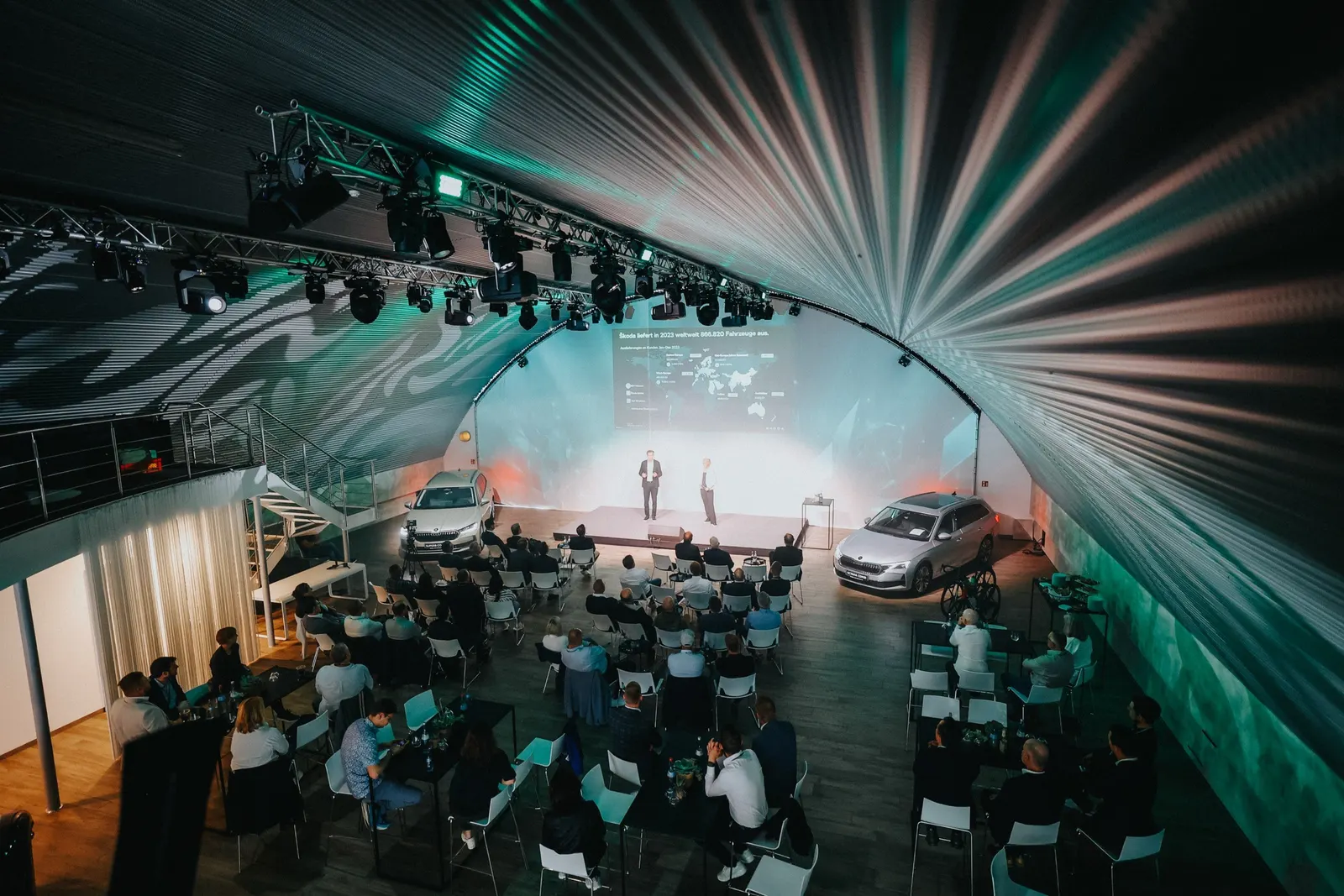 Publikum bei einer Präsentation im Hangar unter grünen Lichtmustern
